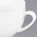 A close-up of a white CAC Majesty European bone china cup with a handle.