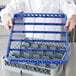 A chef holding a blue plastic tray with a Noble Products blue plastic glass rack extender.