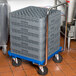 A Vollrath dolly with a stack of grey plastic crates.