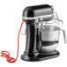 A black and silver KitchenAid commercial mixer with a wire attached.