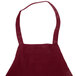 A burgundy Chef Revival apron with white straps.