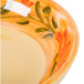 A close up of a Venetian bowl with orange and green flowers on it.