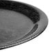 A close up of a GET Etchedware black melamine plate with a wavy pattern on the rim.