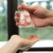 A hand holding an LK Packaging candy bag full of peppermint candies.