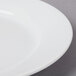A close-up of a CAC Harmony white porcelain plate with a thin rim.