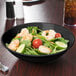 A black Elegance melamine bowl filled with salad, shrimp, and vegetables.