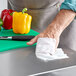 A person using WipesPlus sanitizing wipes to clean a surface in a professional kitchen.