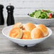 A bowl of salad and a plate of bread in a white Milano melamine bowl.