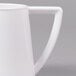 A close-up of a white plastic creamer with a handle.