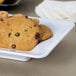 A white rectangular Milano plate with chocolate chip cookies on it.
