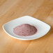 A small white plate with a pile of pink powder on it.