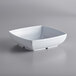 A white square bowl with a lid on a gray surface.