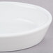 A Hall China bright white oval baker dish on a gray surface.