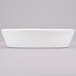 A close up of a white oval baker dish on a white surface.