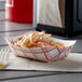 A red check paper food tray filled with coleslaw and carrots on a table.
