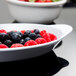 A white oval side dish filled with strawberries, raspberries, and blueberries.