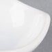 An American Metalcraft white ceramic sauce cup with a curved edge.
