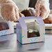 A gloved hand holds a window Easter egg candy box filled with chocolates.