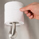 A hand holding a Bobrick spare toilet roll over a metal pipe.