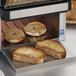 A Waring commercial conveyor toaster toasting bread on a tray.