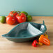 A triangle shaped bowl filled with tomatoes and peppers.