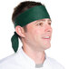 A man wearing a hunter green chef neckerchief on his head.