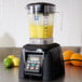 A Waring commercial blender with yellow liquid in it on a counter.