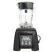 A Waring commercial blender with a clear container on a counter.