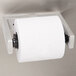 A Bobrick toilet paper roll holder with a satin finish and controlled delivery holding a roll of toilet paper.