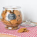 A glass jar of ginger snaps with an American Metalcraft chalkboard label on a table.