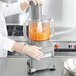 A person in a white coat using a Waring 6 qt. bowl cover with feed chute on a blender bowl on a counter in a professional kitchen.