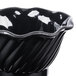 A close-up of a black tulip dessert dish with a wavy edge.