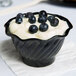 A black GET tulip dessert dish filled with yogurt and blueberries.