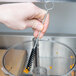 A hand using a Waring cleaning brush to clean a food processor.