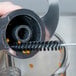 A person uses the Waring cleaning brush to clean a circular food processor part.