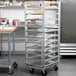 A Metro aluminum roll-in refrigerator rack holding sheet pans of food.