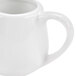 A close-up of a white CAC porcelain creamer with a handle.