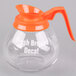 A Grindmaster glass coffee decanter with an orange decaf handle.