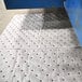 A Spilfyter heavy weight gray absorbent mat with holes in it.