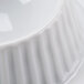 A close-up of a white CAC porcelain butter dish with a rippled design.