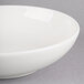 A Homer Laughlin bright white china soup bowl with a white rim on a gray surface.