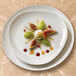 A Homer Laughlin bright white triangle china plate with figs and cream on a table with a plate of fruit.