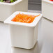 A white Cambro food pan with shredded carrots inside.