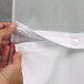 A person attaching Hookless white shower curtain with gray waves to a rod using a zipper.