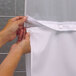 A person's hands opening a white shower curtain.