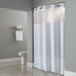 A white Hookless shower curtain with a Poly-Voile translucent window hanging in a bathroom.
