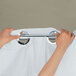 Hands using a metal bar to hang a white Hookless shower curtain.