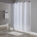 A white Hookless pin dot shower curtain hanging in a bathroom with a shower curtain rod.