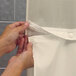 A person opening a beige shower curtain with magnets using their hand.