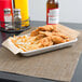 A tray of fried chicken and fries lined with a Choice Natural Kraft deli wrap on a table.